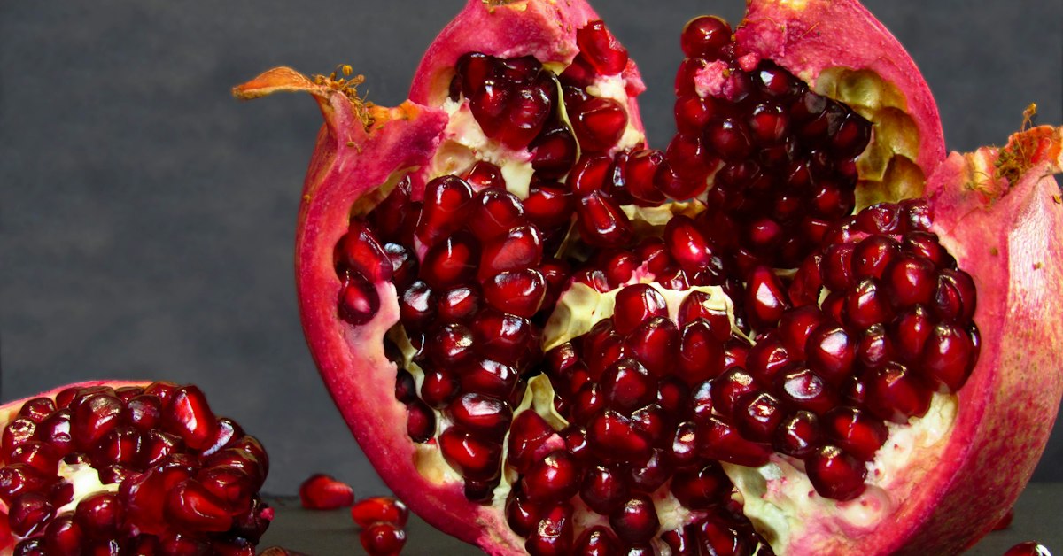 Granada partida por la mitad mostrando sus arilos frescos, fruta de temporada para la dieta keto